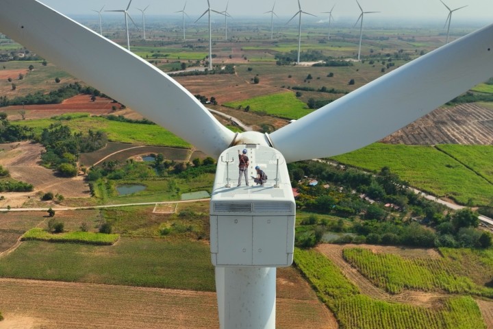 engineers standing on top of wind turbine