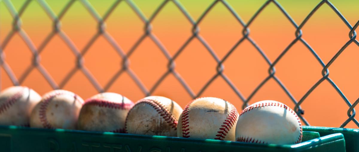 baseballs-lined-up-against-chain-link-fence