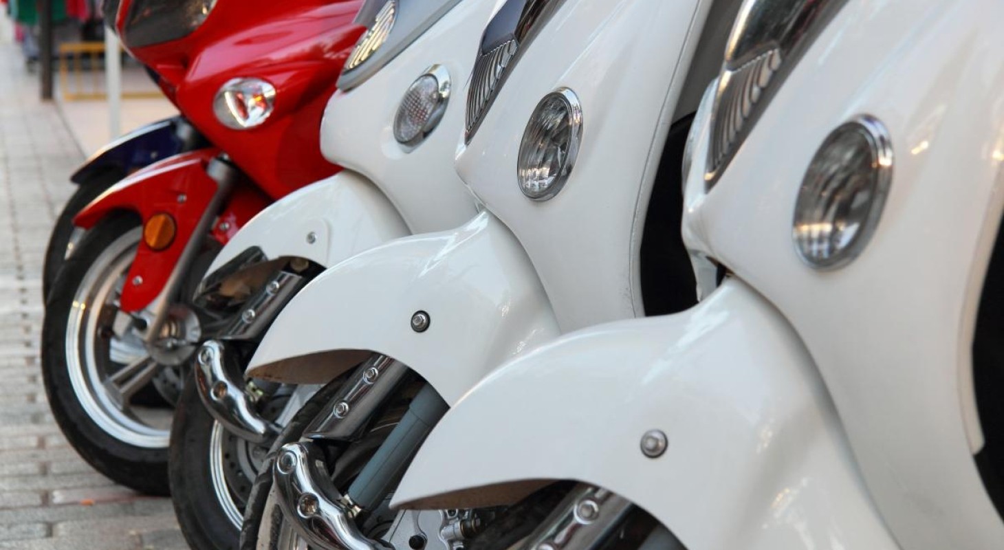 parked row of three white scooters followed by one red scooter