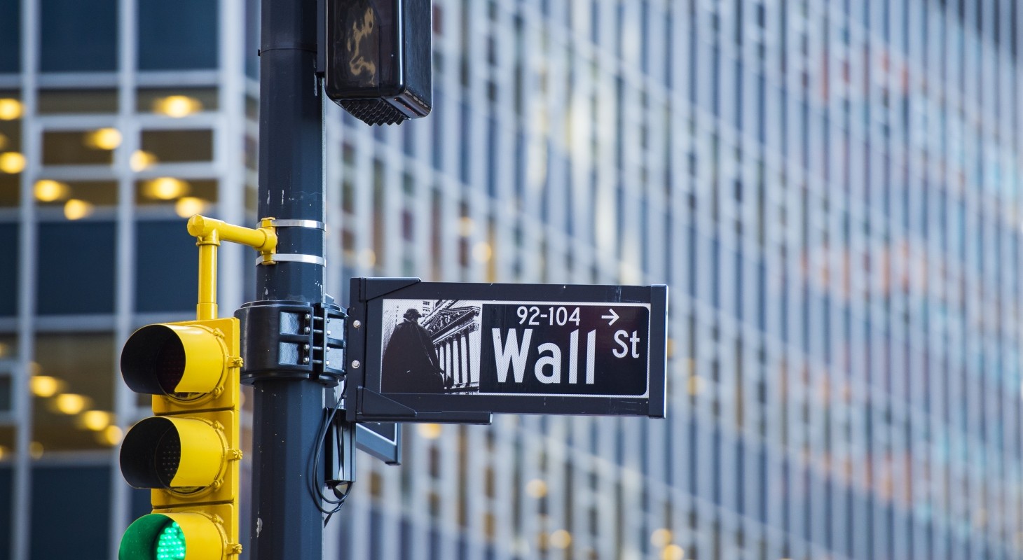 close up of green traffic light and wall street sign