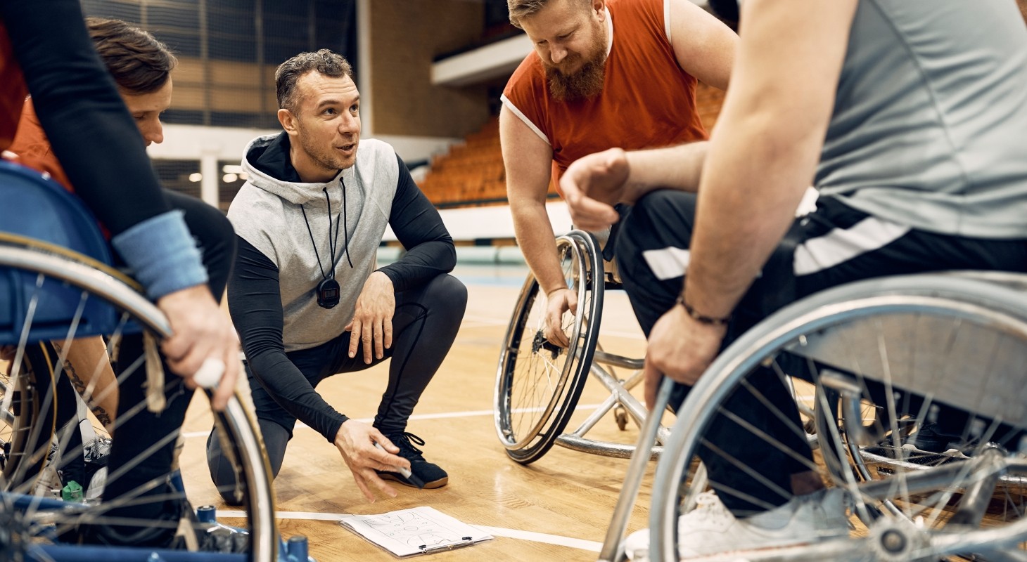 coach of basketball team talking with his players in wheelchairs