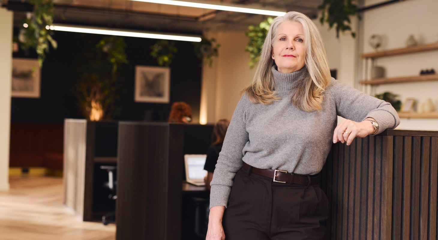 woman with long gray hair in business casual dress looking at camera