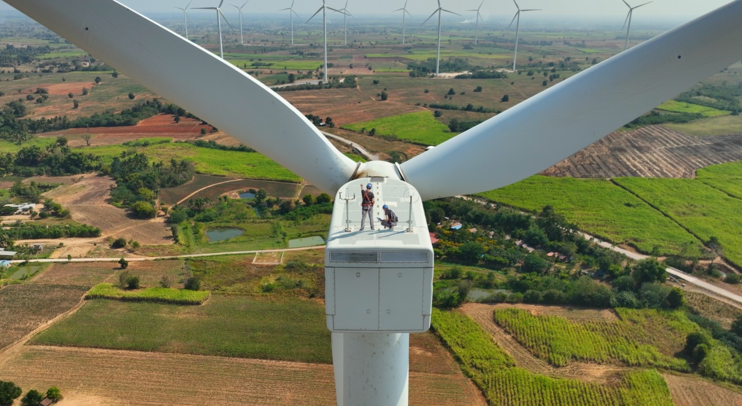 engineers standing on top of wind turbine