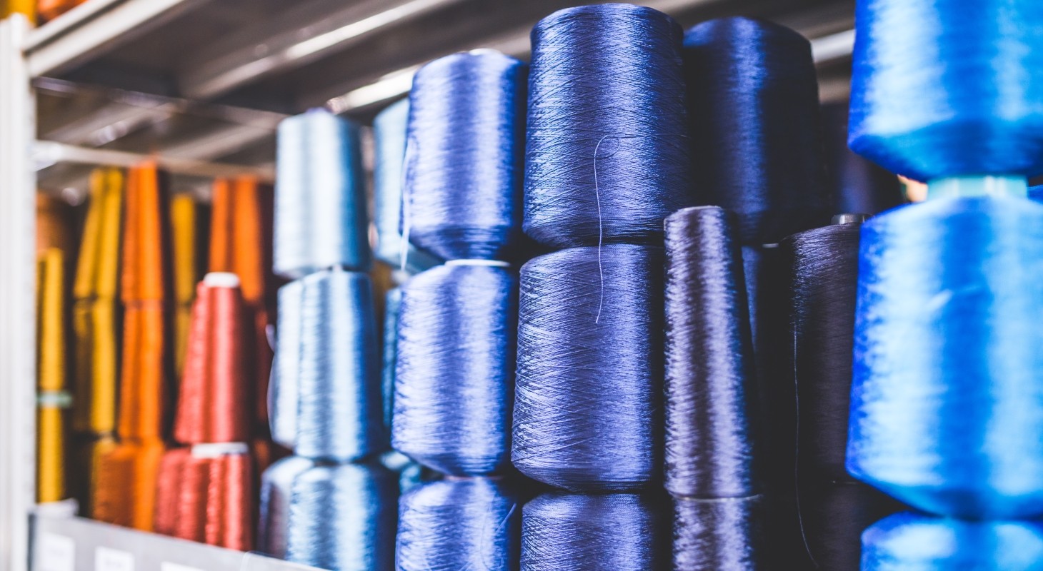 orange red blue and purple spools of thread stacked on shelf