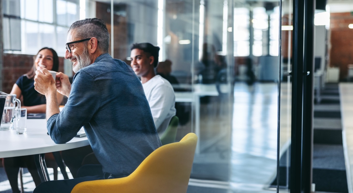 smiling older executive leader at modern table with coworkers