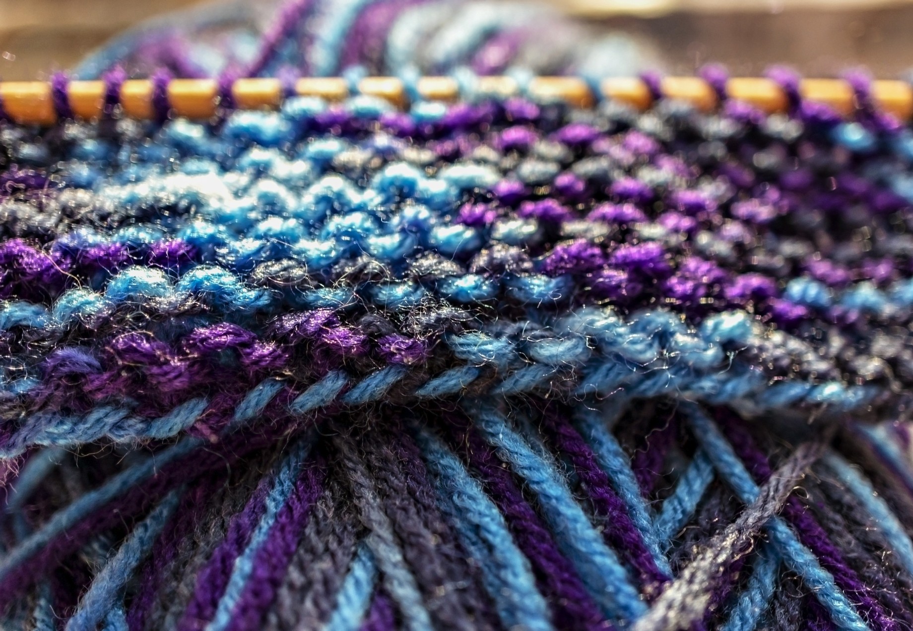 purple blue and gray yarns woven on knitting needle