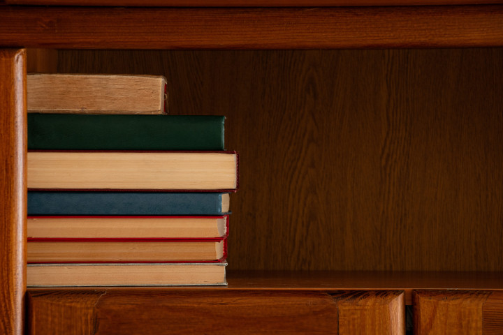 collection of books on a wooden shelf in cabinet