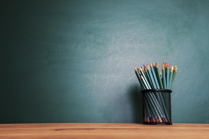 colored pencils in a black cup in front of green chalkboard