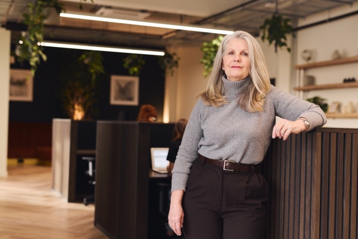 woman with long gray hair in business casual dress looking at camera