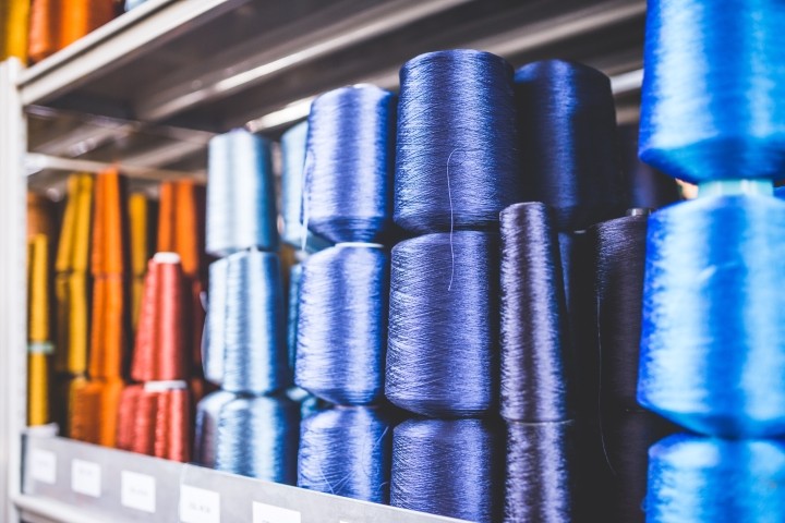 orange red blue and purple spools of thread stacked on shelf