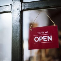 red sign hanging in window that says yes we are open