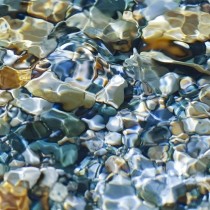 sunlight shining through water to illuminate multi-colored pebbles below